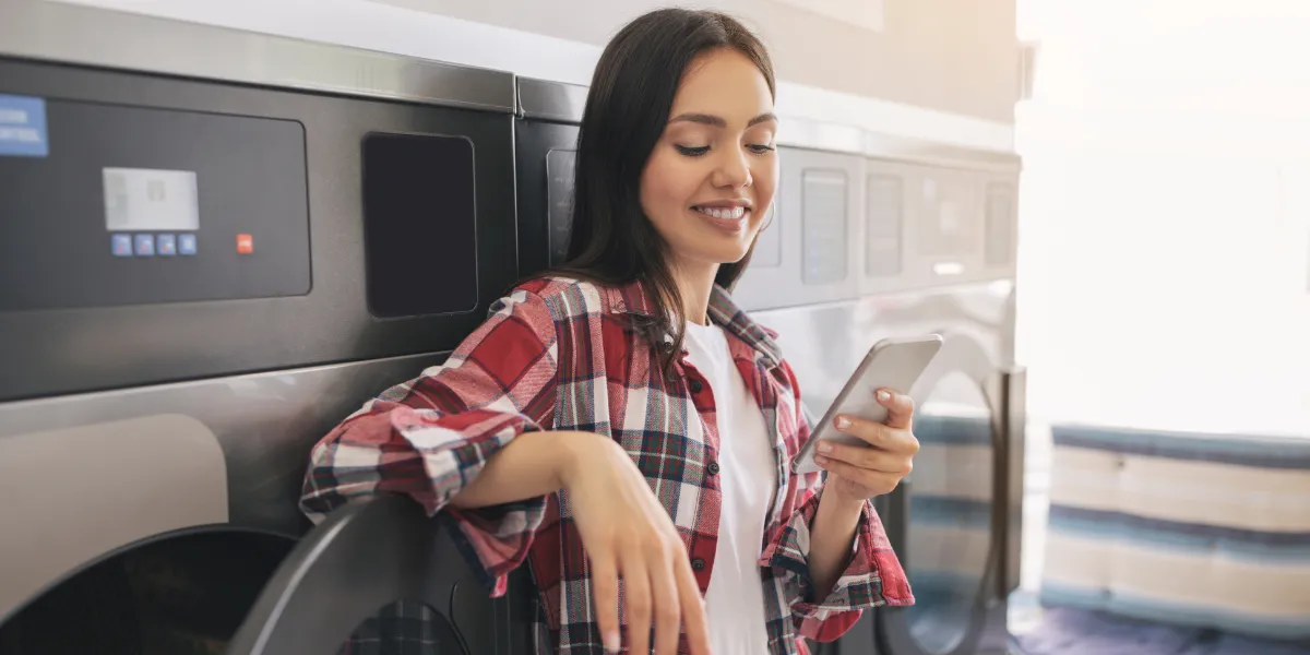 woman looking at her phone in laundromat