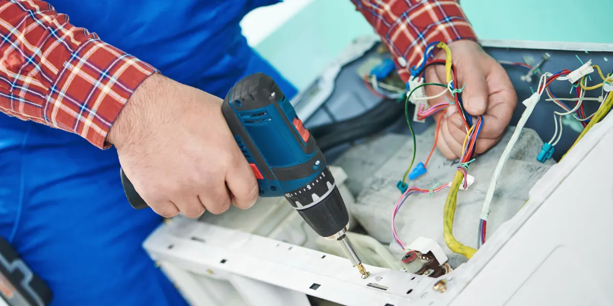 man repairing back of washer